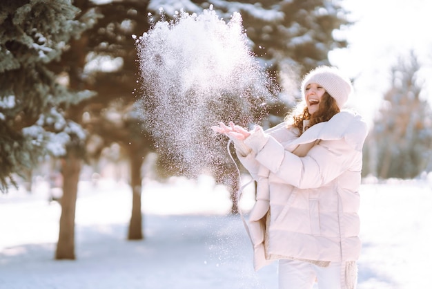 Giovane donna in abiti in stile invernale che cammina nel parco innevato Vacanze di moda invernale