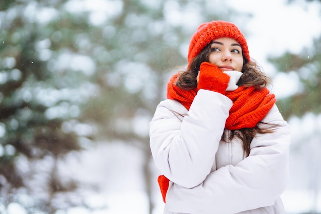 Giovane donna in abiti in stile invernale sullo sfondo della foresta innevata Vacanze nella natura