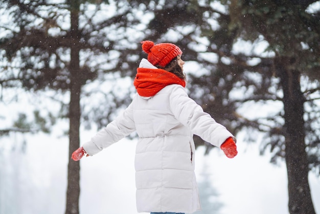 Giovane donna in abiti in stile invernale sullo sfondo della foresta innevata Vacanze nella natura