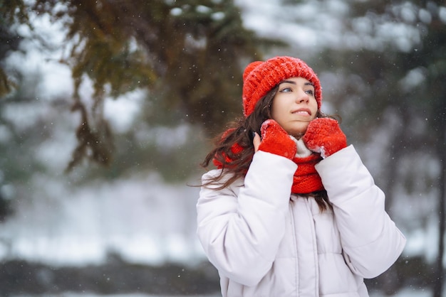 Giovane donna in abiti in stile invernale sullo sfondo della foresta innevata Vacanze nella natura