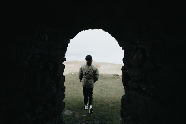 Giovane donna in abiti invernali vista posteriore che cammina sullo stile del film con sfondo autunno nebbioso montagna, hipster viaggiatore riprese video natura nebbia paesaggio, concetto di vacanza hobby, spazio di copia