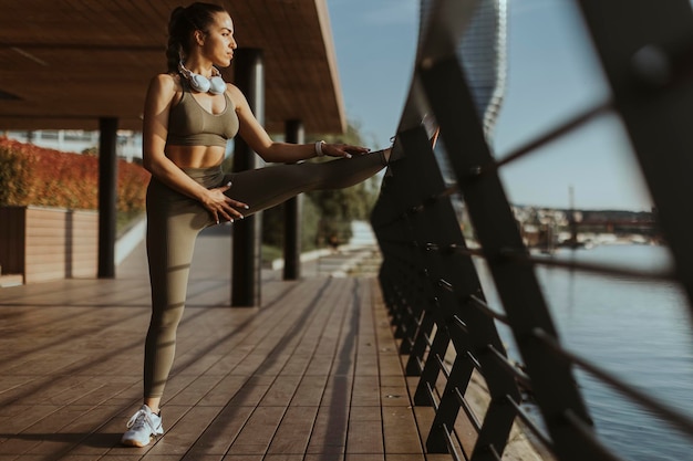 Giovane donna in abiti sportivi che si esercita su una passeggiata sul fiume