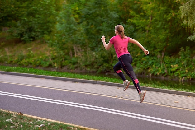 Giovane donna in abiti sportivi corre lungo il sentiero del parco