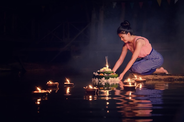 Giovane donna in abiti tradizionali in ginocchio vicino al lago di notte