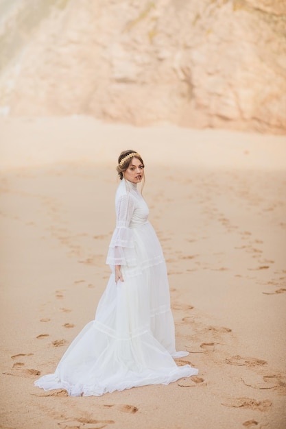 giovane donna in abito bianco che cammina sulla spiaggia