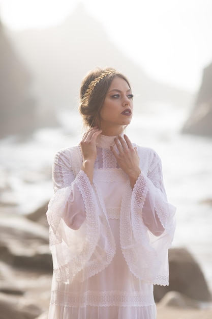 giovane donna in abito bianco che cammina sulla spiaggia