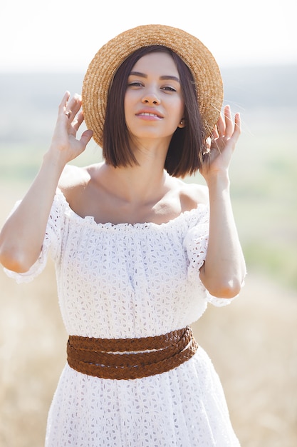 Giovane donna in abito bianco e cappello