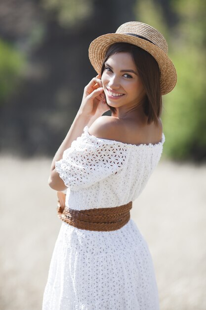 Giovane donna in abito bianco e cappello