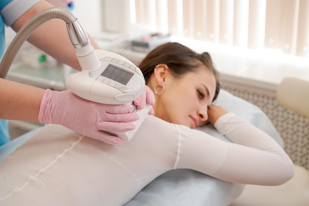 Giovane donna in abito bianco speciale riceve un massaggio anticellulite nella spa