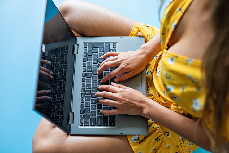giovane donna in abito giallo che lavora al computer portatile