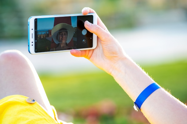 Giovane donna in abito giallo estivo prendendo selfie