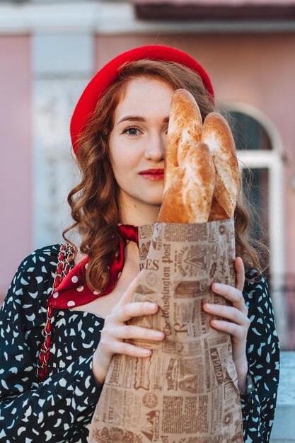 Giovane donna in abito nero in possesso di un pacchetto di carta di baguette francesi Foto di cibo di panetteria