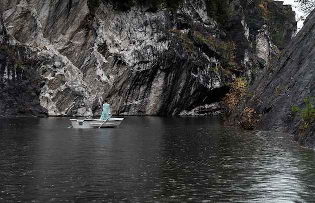 Giovane donna in abito turchese che naviga in barca bellissimo paesaggio di lago di montagna