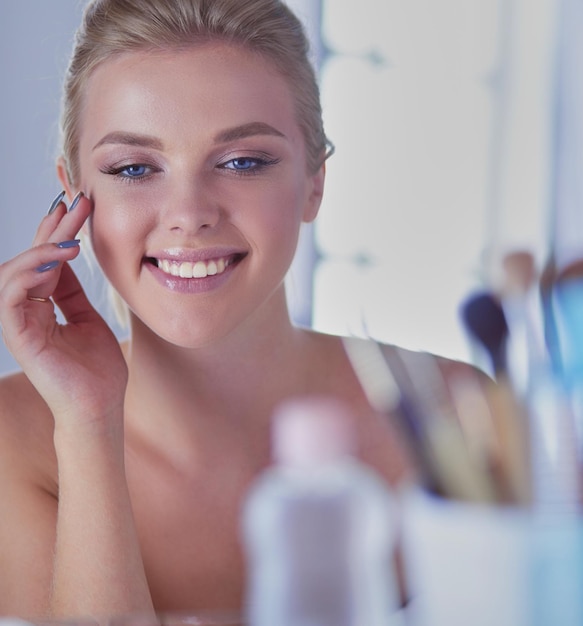 Giovane donna in accappatoio che guarda nello specchio del bagno