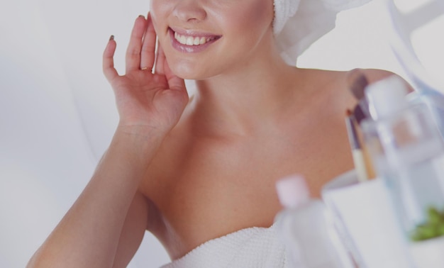 Giovane donna in accappatoio che guarda nello specchio del bagno