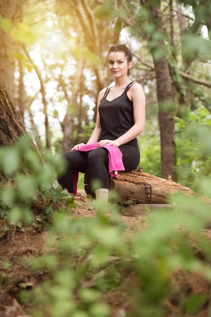 Giovane donna in appoggio dopo l'esecuzione nella foresta boscosa Area formazione ed esercizio per Trail Run Marathon Endurance Fitness uno stile di vita sano Concept