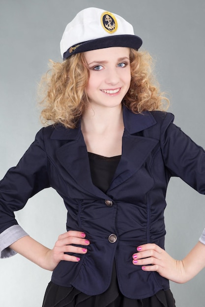 giovane donna in berretto da capitano su sfondo grigio
