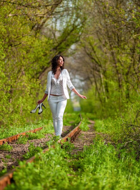 Giovane donna in bianco sui binari in natura.