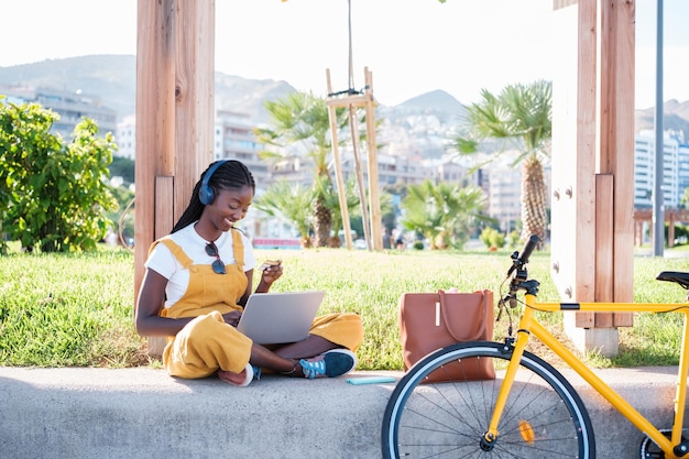 Giovane donna in bicicletta che fa shopping all'aperto con il suo laptop concetto di stile di vita vita cittadina all'aperto