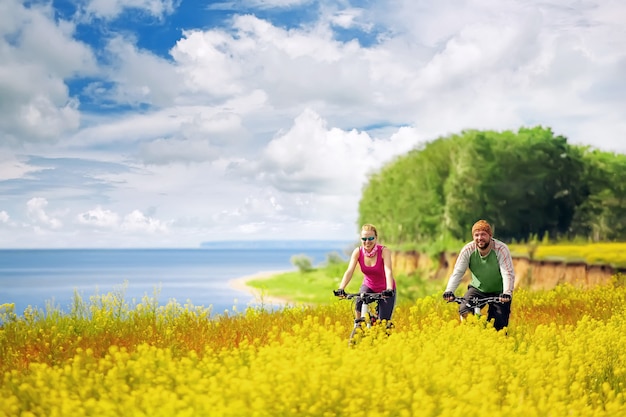 Giovane donna in bicicletta nel campo di fiori gialli