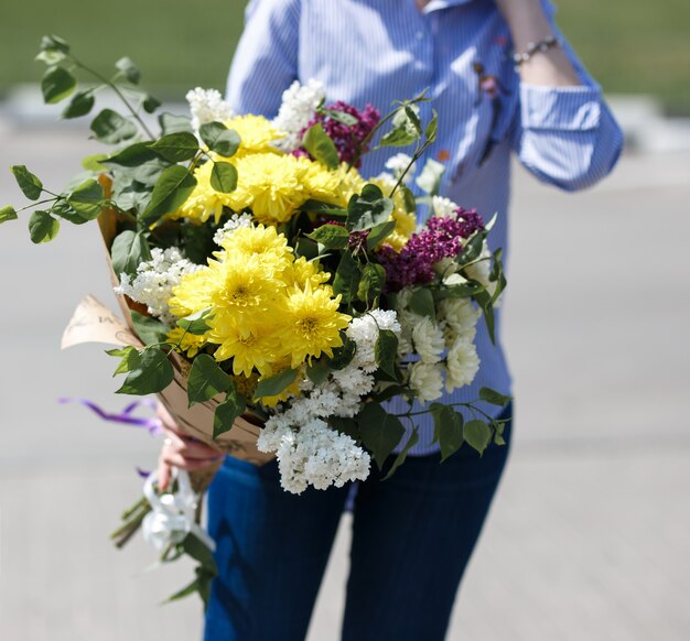 Giovane donna in blusa di cotone blu e jeans in possesso di un bouquet.