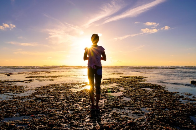 Giovane donna in buona salute che pratica yoga sulla spiaggia al tramonto Donna forte di fiducia sotto il tramonto