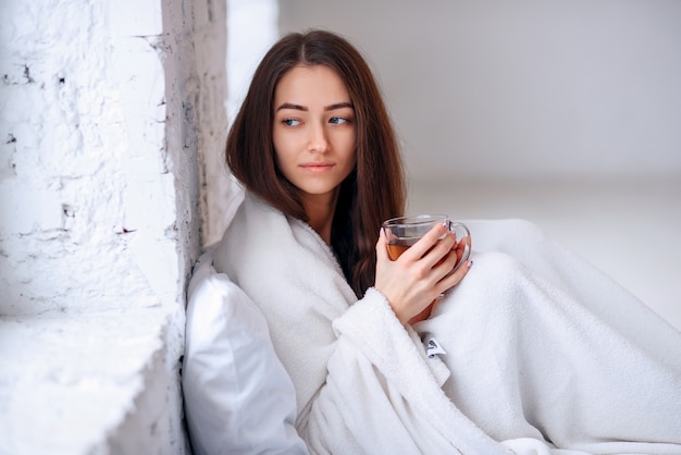 giovane donna in caldo plaid con calda tazza di tè nelle mani