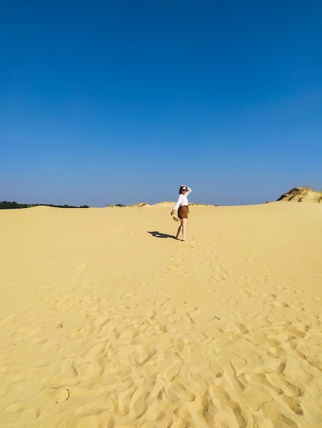 Giovane donna in camicetta bianca e pantaloncini marroni che camminano nel deserto