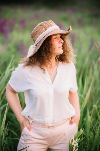 Giovane donna in camicia bianca in campo di lupini viola e rosa