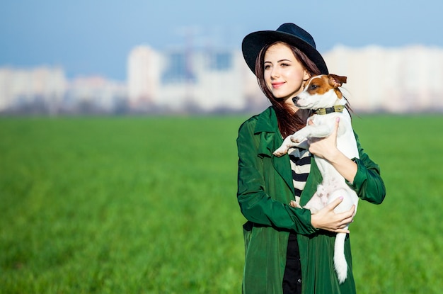 Giovane donna in cappello e mantello con cane