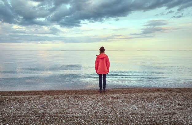 Giovane donna in cappello sulla spiaggia la sera.