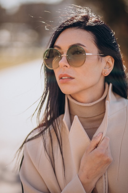 Giovane donna in cappotto beige che cammina per strada