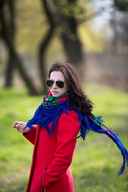 Giovane donna in cappotto e occhiali da sole