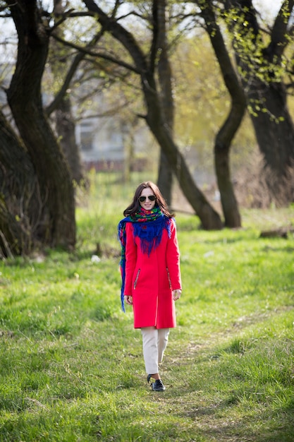 Giovane donna in cappotto e occhiali da sole