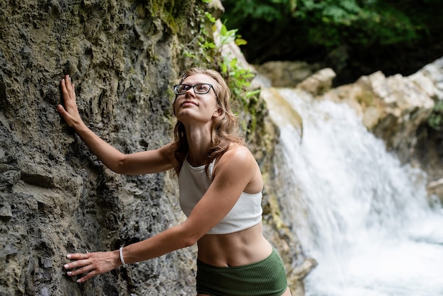 Giovane donna in costume da bagno che si gode la cascata