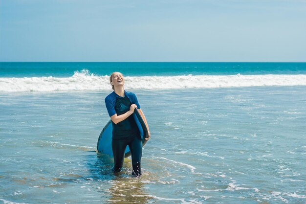 Giovane donna in costume da bagno con surf per principianti pronti a navigare. Emozioni positive.