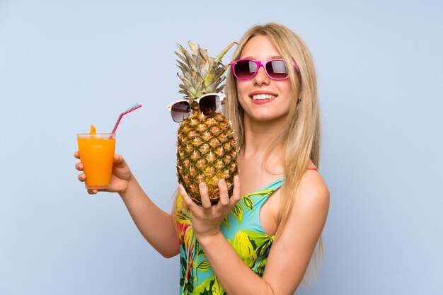 Giovane donna in costume da bagno in possesso di un ananas con occhiali da sole