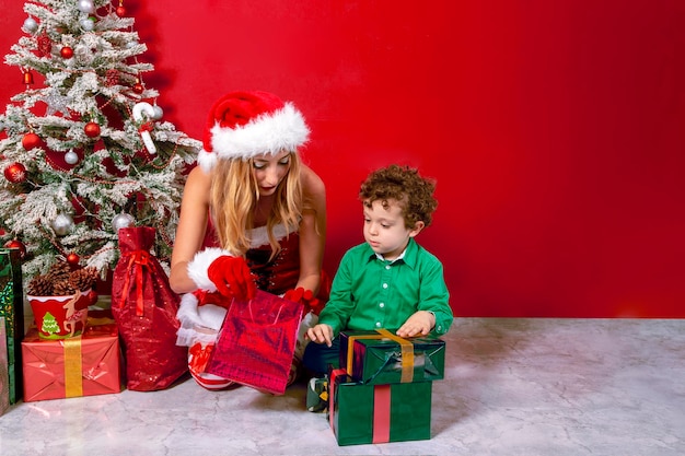 Giovane donna in costume di Babbo Natale accanto al bambino con regali di Natale