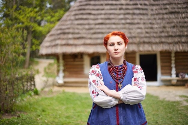 Giovane donna in costume nazionale ucraino Giovane signora sorridente in abiti tradizionali vicino alla vecchia casa di legno Pace in Ucraina