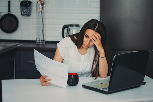 Giovane donna in cucina a lavorare con il computer portatile