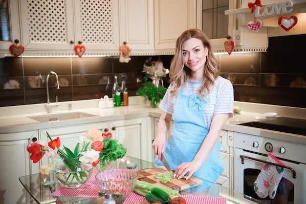 Giovane donna in cucina a preparare un'insalata