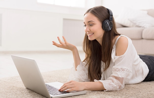 Giovane donna in cuffie in linea sul computer portatile