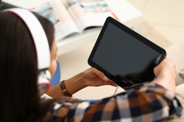 Giovane donna in cuffie utilizzando il computer tablet