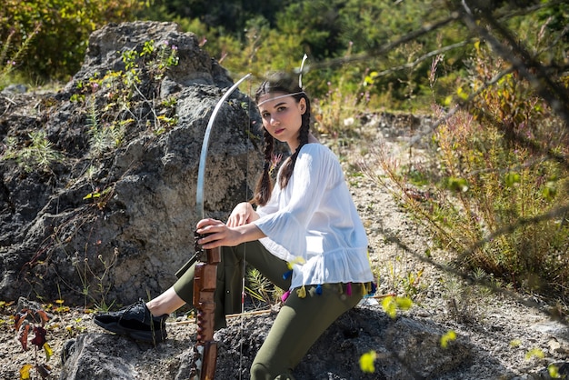 Giovane donna in grande stile come popoli nativi d'America con arco e frecce in natura