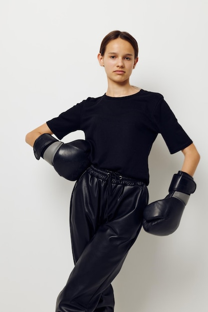 Giovane donna in guantoni da boxe in pantaloni neri e una maglietta isolata sullo sfondo