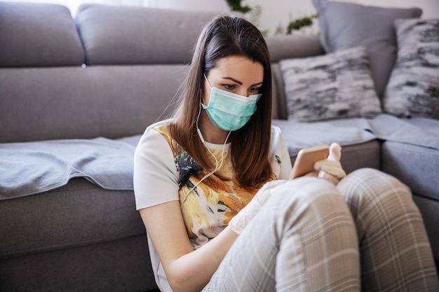 Giovane donna in isolamento avendo una telefonata. Comunicazione in linea durante la quarantena. Resta a casa.