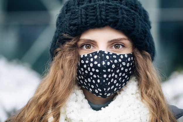 Giovane donna in maschera facciale medica in piedi contro la città.