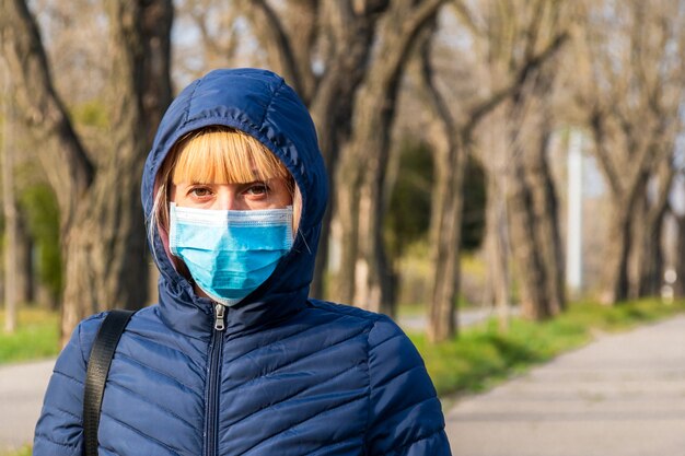 Giovane donna in maschera protettiva sul parco della città con l'inquinamento atmosferico