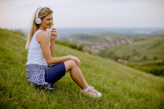 Giovane donna in natura ascoltando musica in cuffia