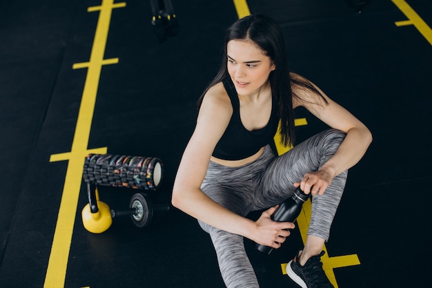 Giovane donna in palestra, bevendo acqua